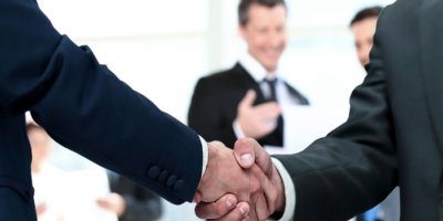 Two men in business suits shaking hands.